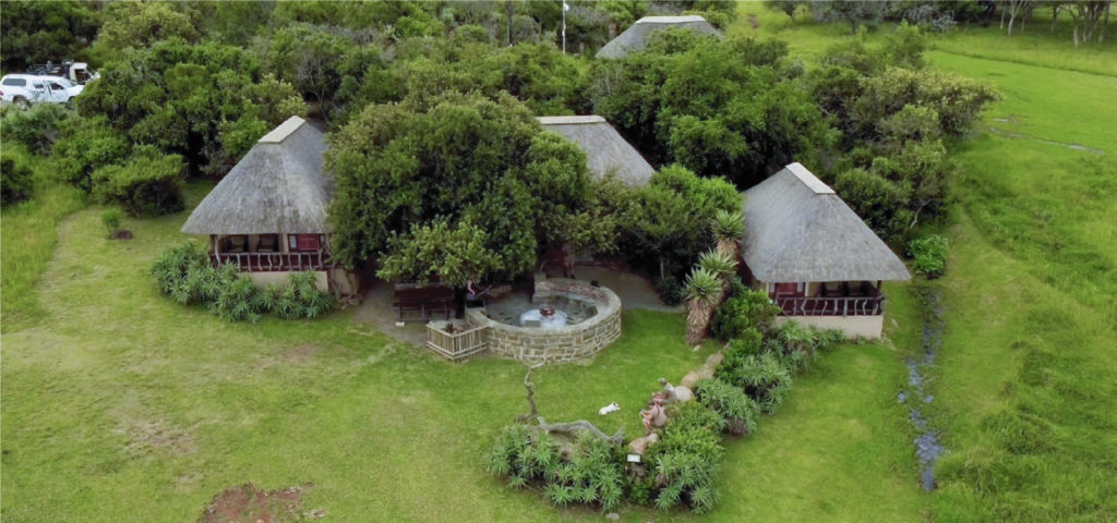 Aerial view of Aloe Africa Hunting Safaris lodge with thatched chalets and lapa amid indigenous bush
