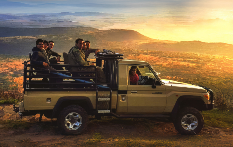 Hunting safari group on game-drive Land Cruiser at golden-hour sunset overlook South Africa
